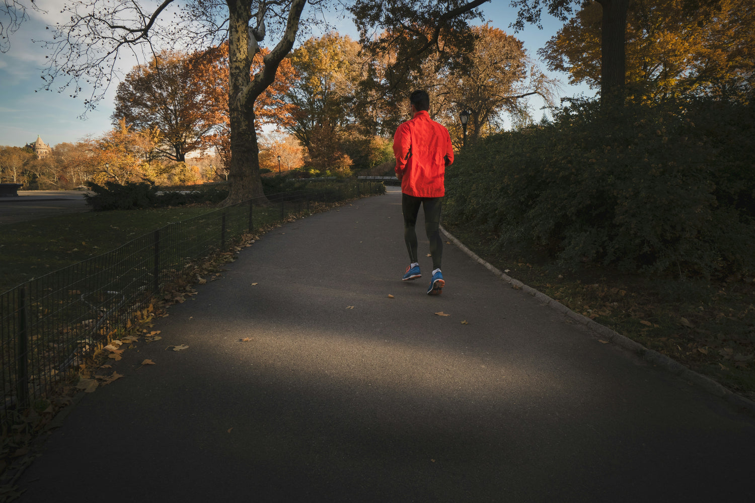 Man wearing a red jacket running in a park